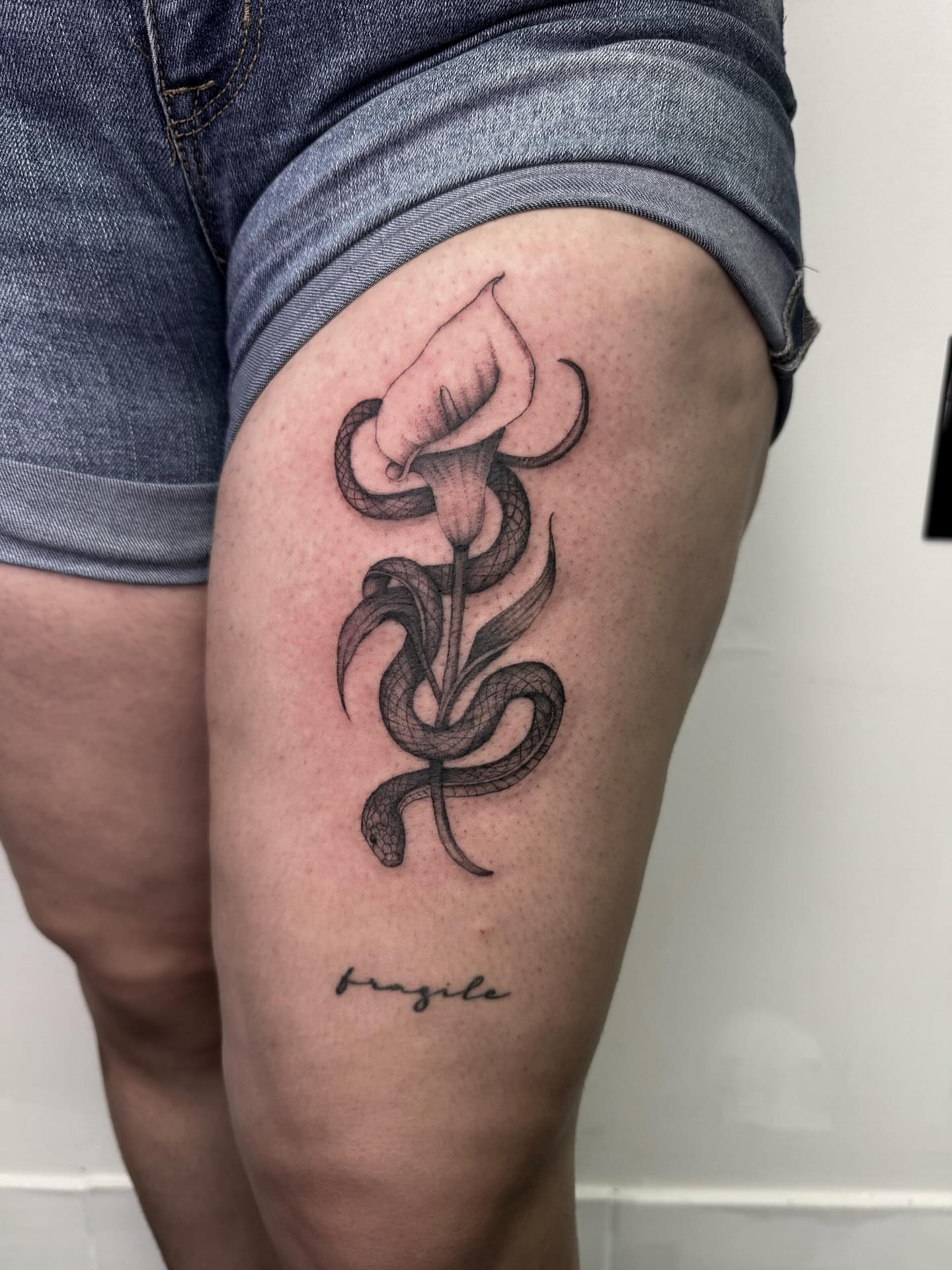 Snake and calla lily tribal tattoo on the thigh by Rachel