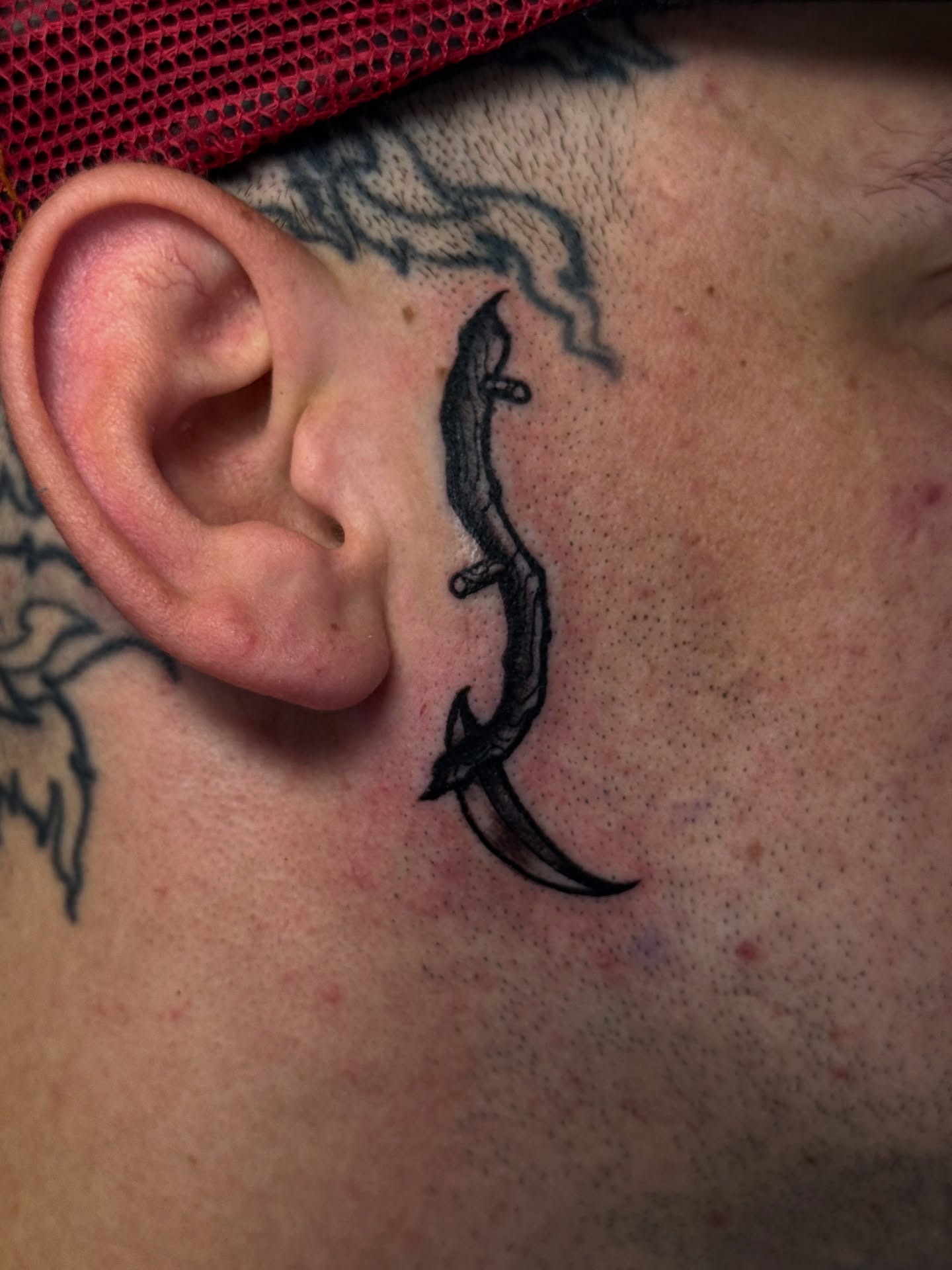 Dagger black and grey tattoo on the neck by Mitch McGarry