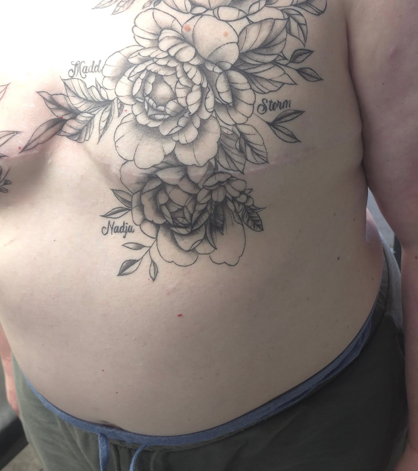 Floral bouquet black and grey tattoo on the chest by Trinity