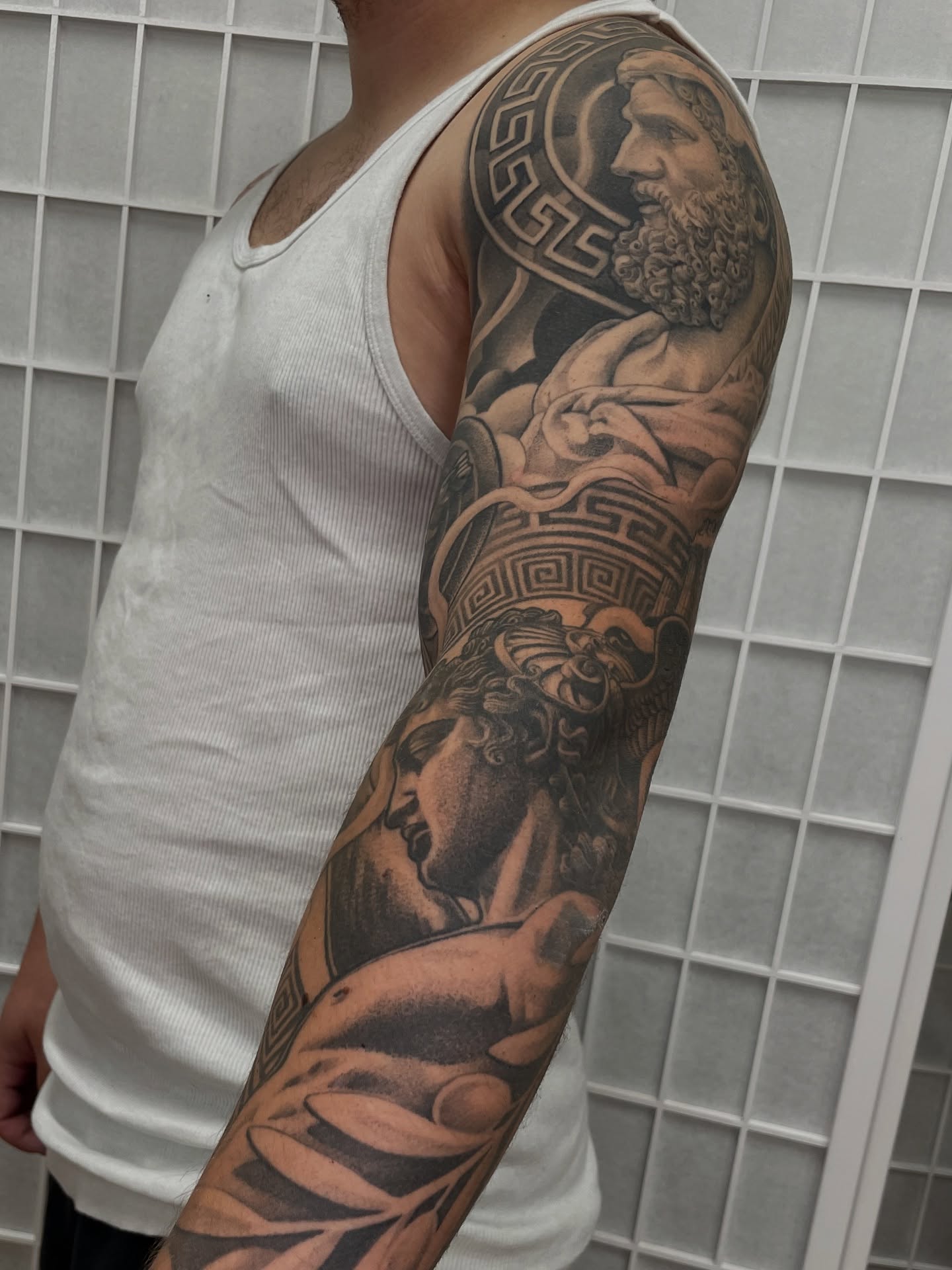Statuesque figures realism tattoo on the upper arm by Collie Mills, Philadelphia, Pennsylvania