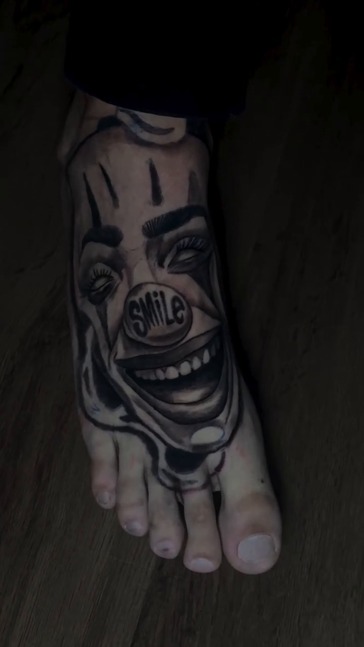 Creepy clown face realism tattoo on the foot by Rebecca Cansler