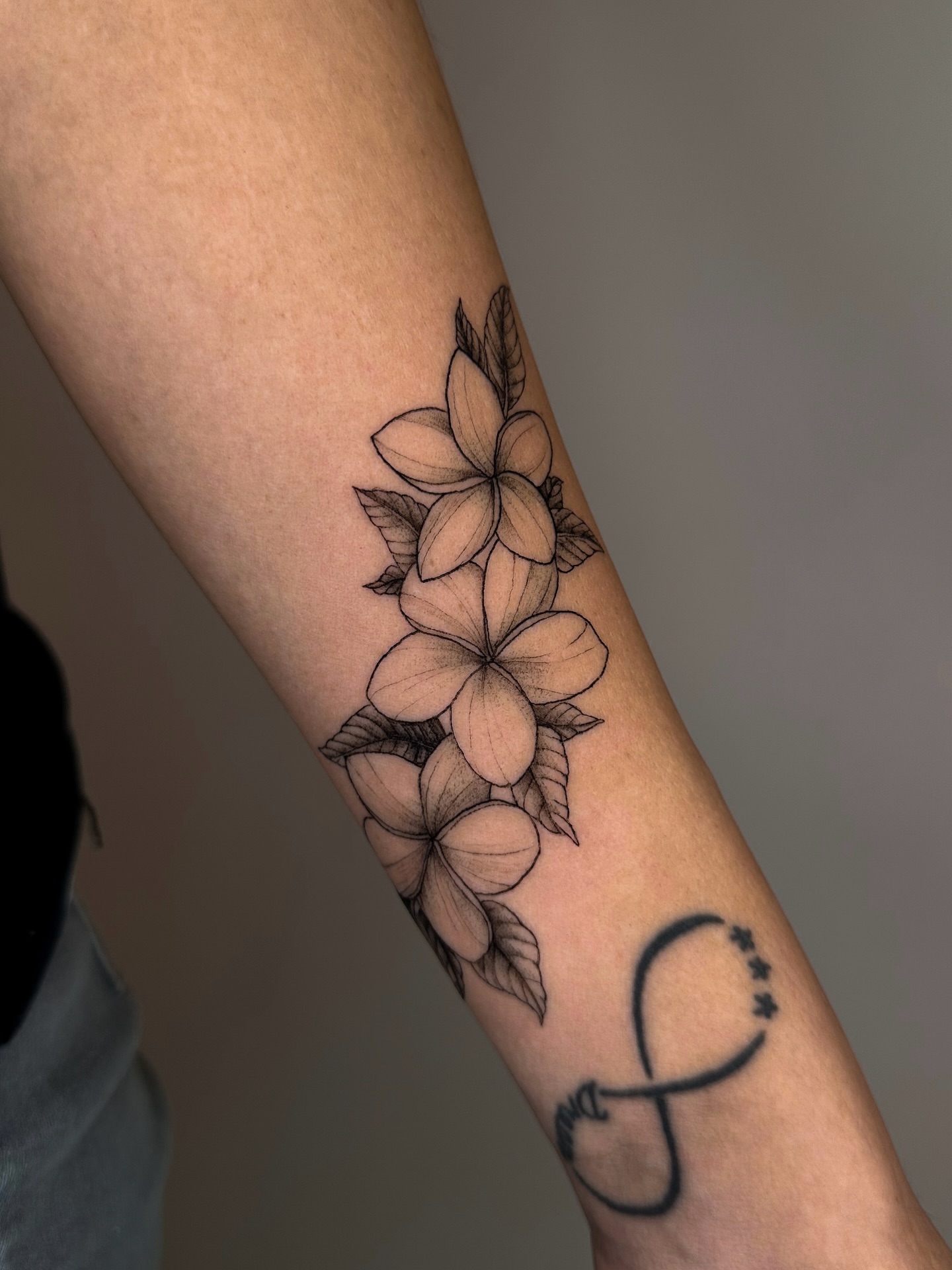 Plumeria flowers black and grey tattoo on the forearm by Lauren
