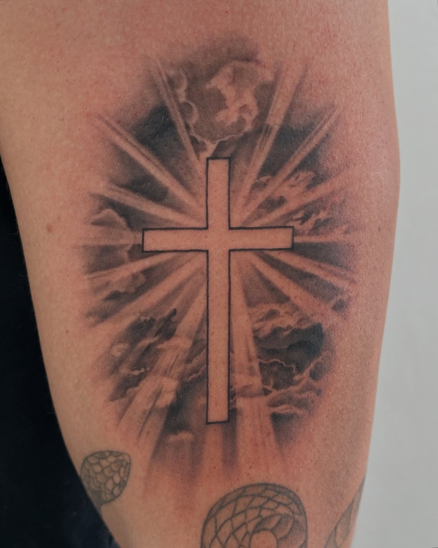 Cross with radiating beams black and grey tattoo on the forearm by Winters Ashurst - St. George tattoo artist