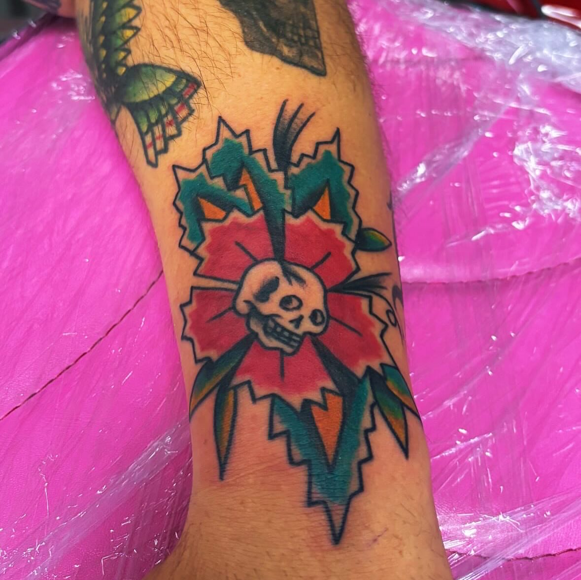 Skull and flower American traditional tattoo on the forearm by 18 and older High End Tattoo