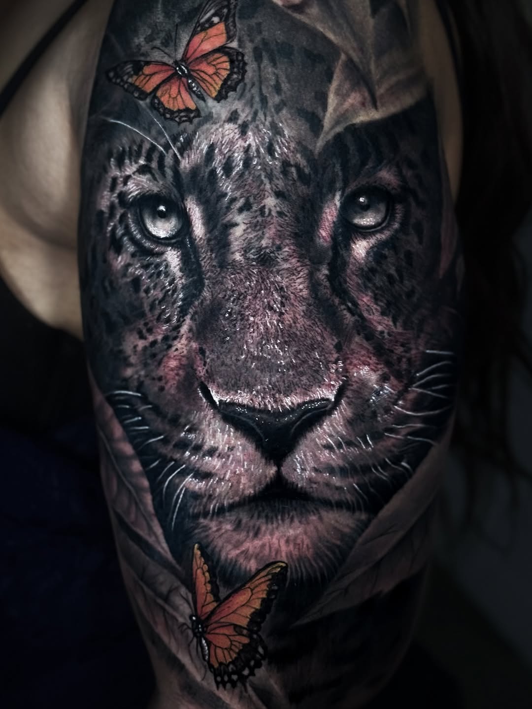 Leopard face with butterflies realism tattoo on the forearm by Rene Artt