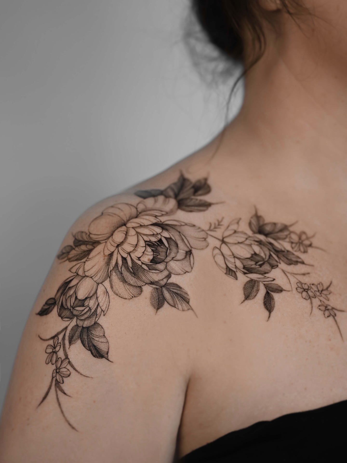 Floral bouquet black and grey tattoo on the shoulder by Anastasiia