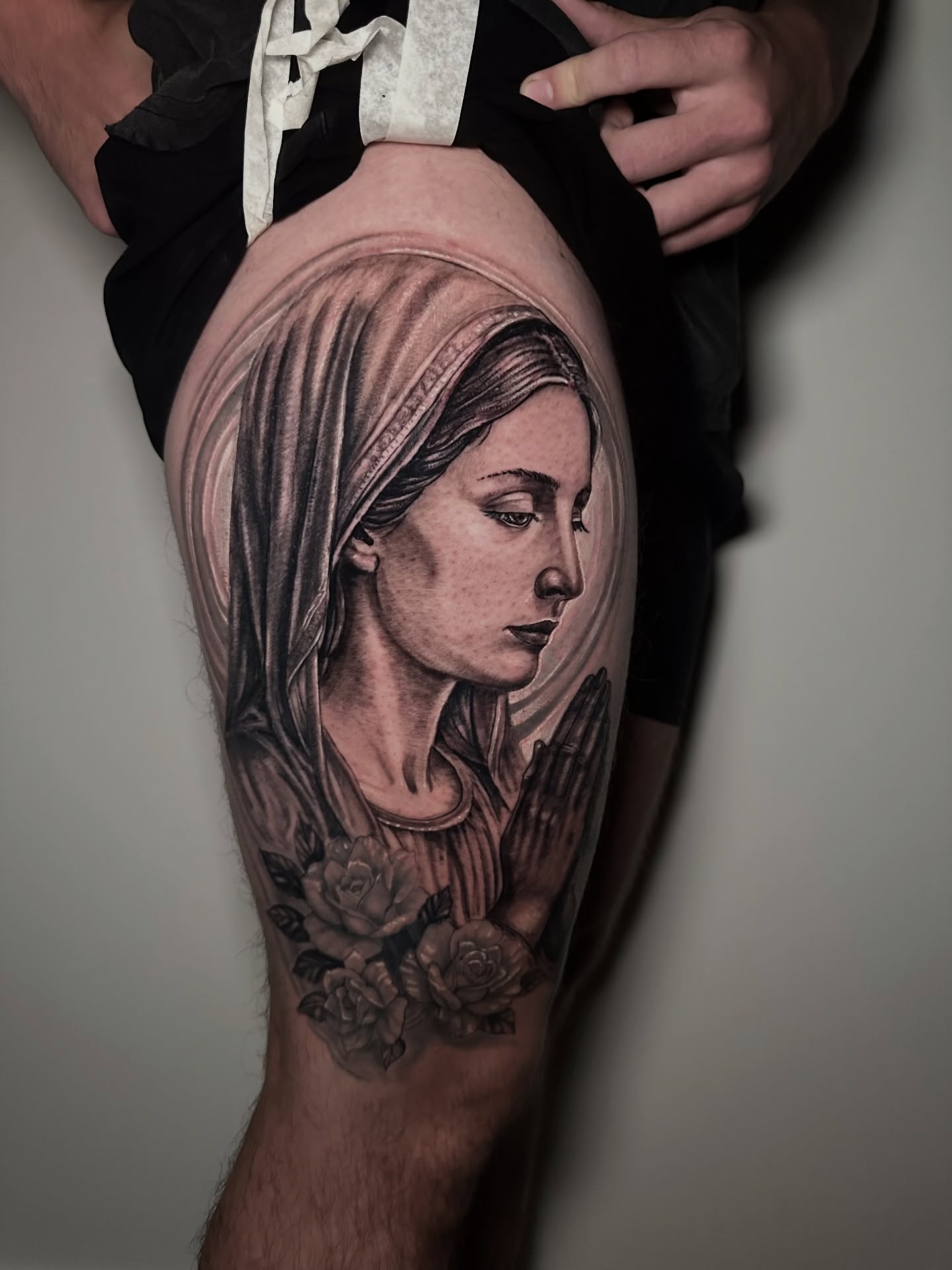 Religious figure realism tattoo on the thigh by Héctor Agudelo