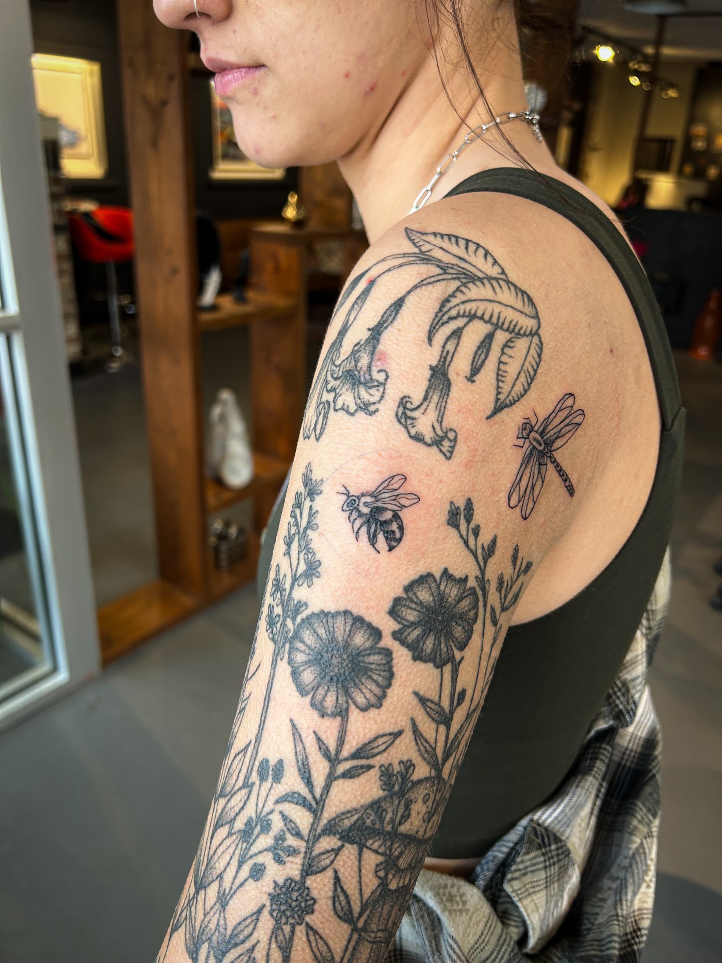 Floral and insect black and grey tattoo on the upper arm by @inkspirationtattoo_co