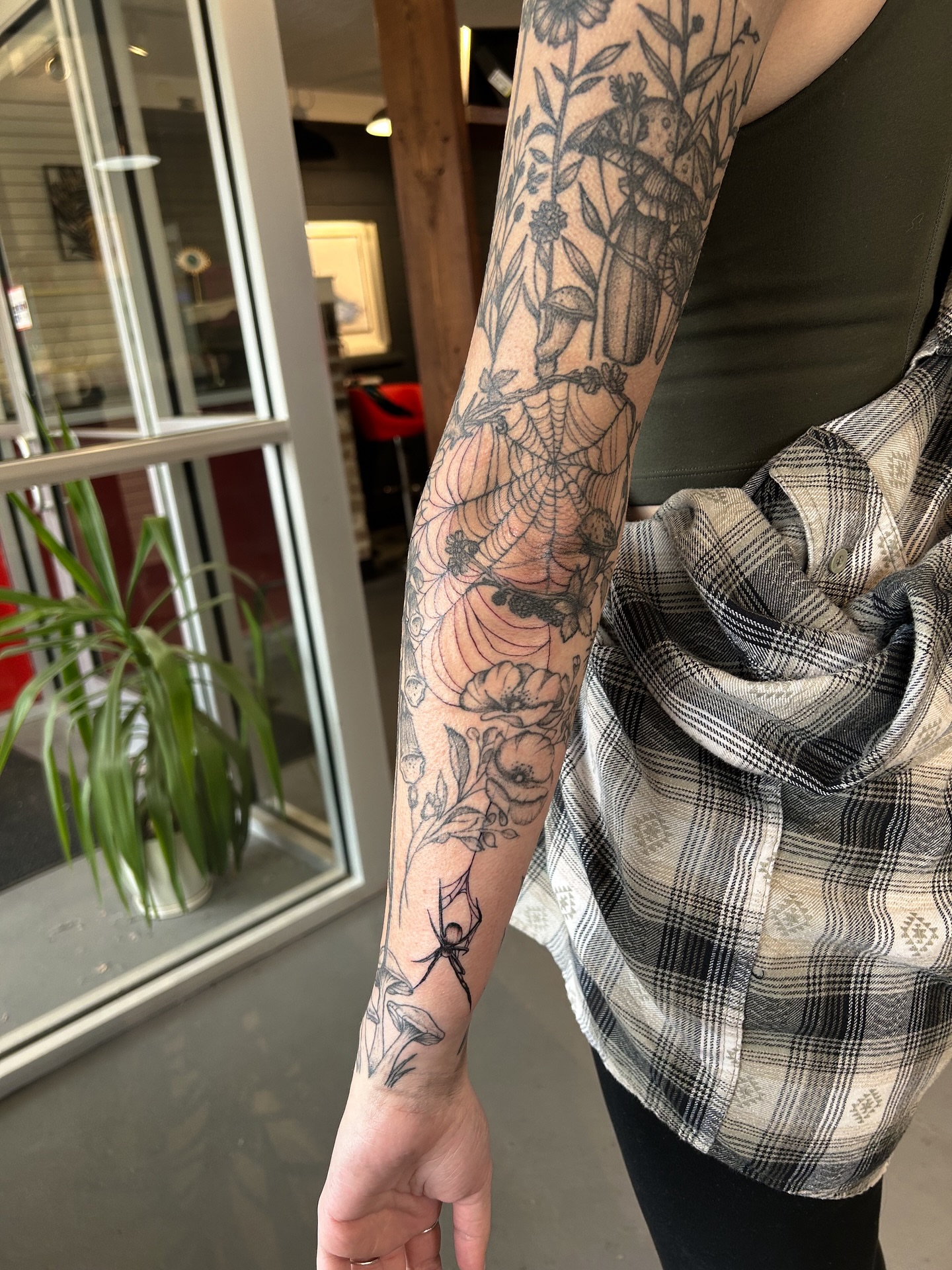 Spiderweb and floral black and grey tattoo on the forearm by @inkspirationtattoo_co