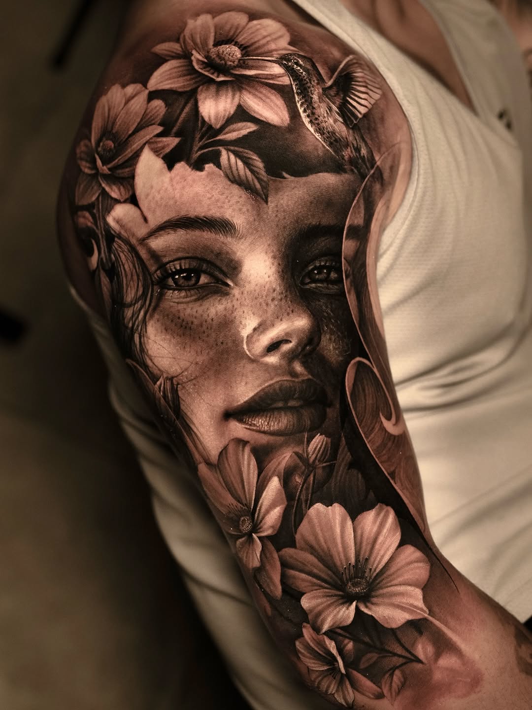 Woman with flowers and hummingbird realism tattoo on the upper arm by @_garart_