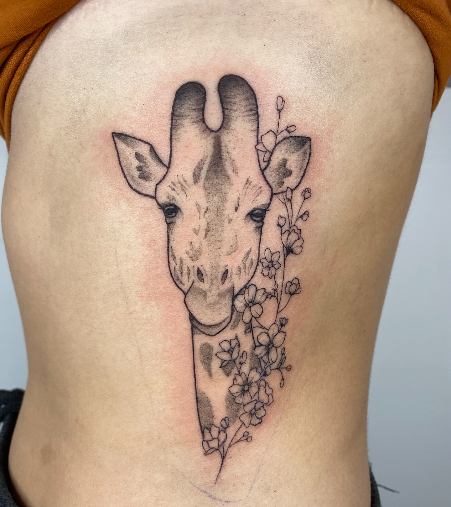 Giraffe black and grey tattoo on the ribs by Nikole