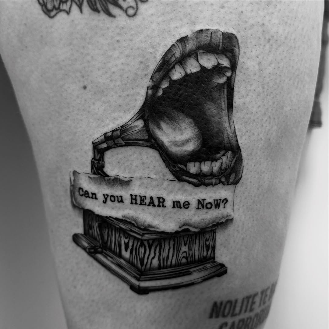 Mouth on gramophone with text surrealism tattoo on the thigh by Kait