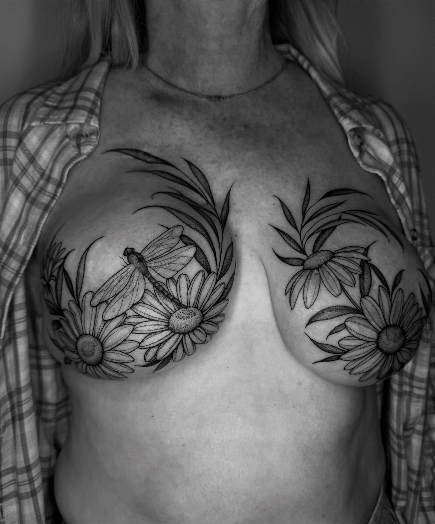 Daisies and dragonfly black and grey tattoo on the chest by Lauren Llerandi