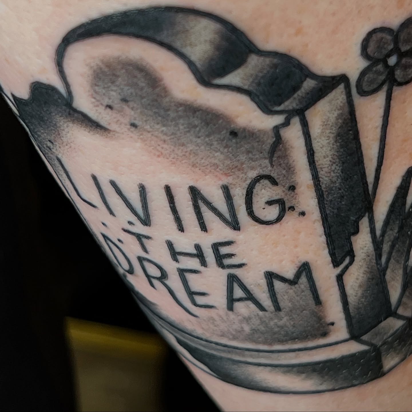 Living the dream black and grey tattoo on the forearm by Cory Miller
