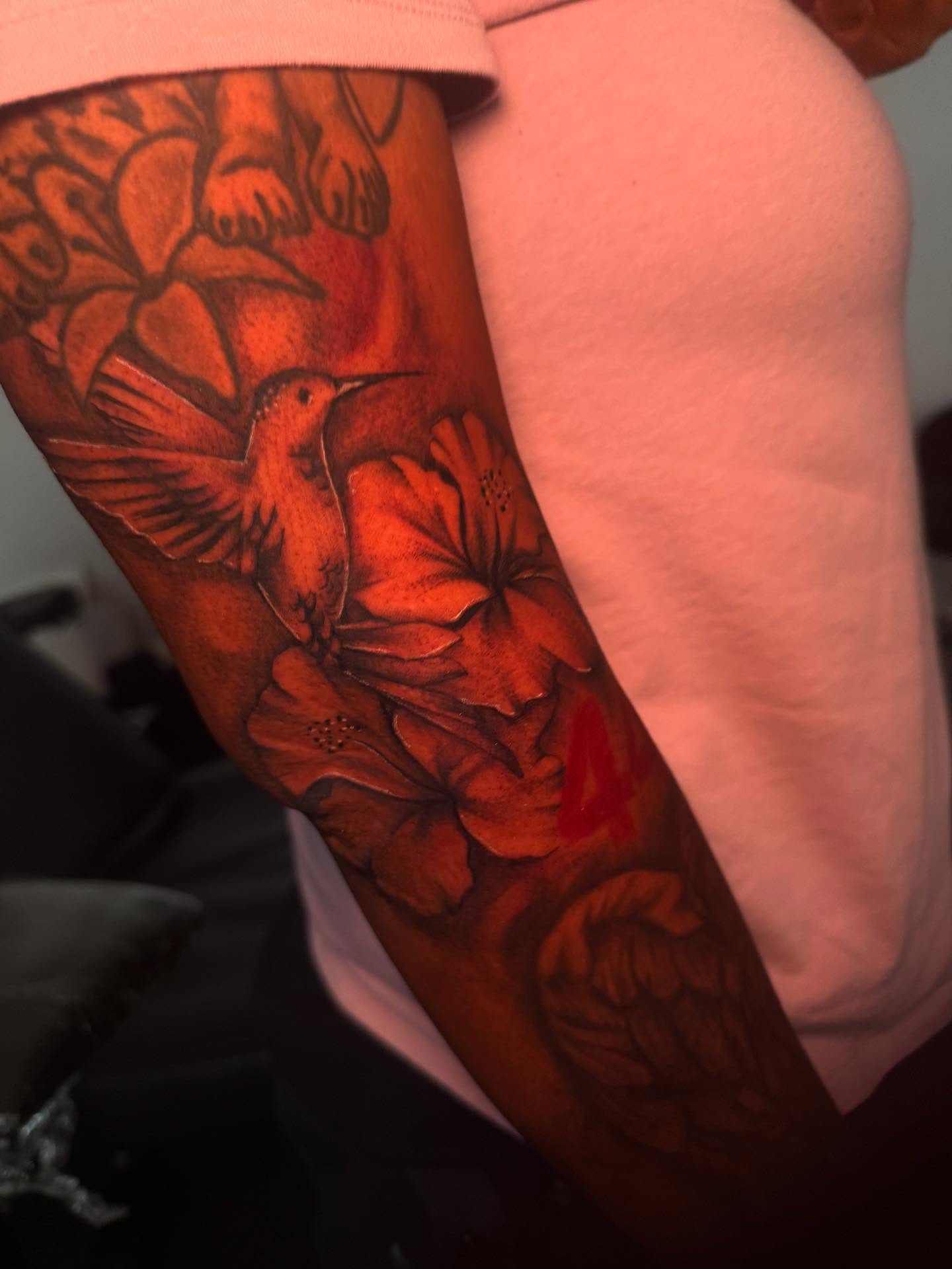 Hummingbird and flowers realism tattoo on the forearm by The Ink Guru.