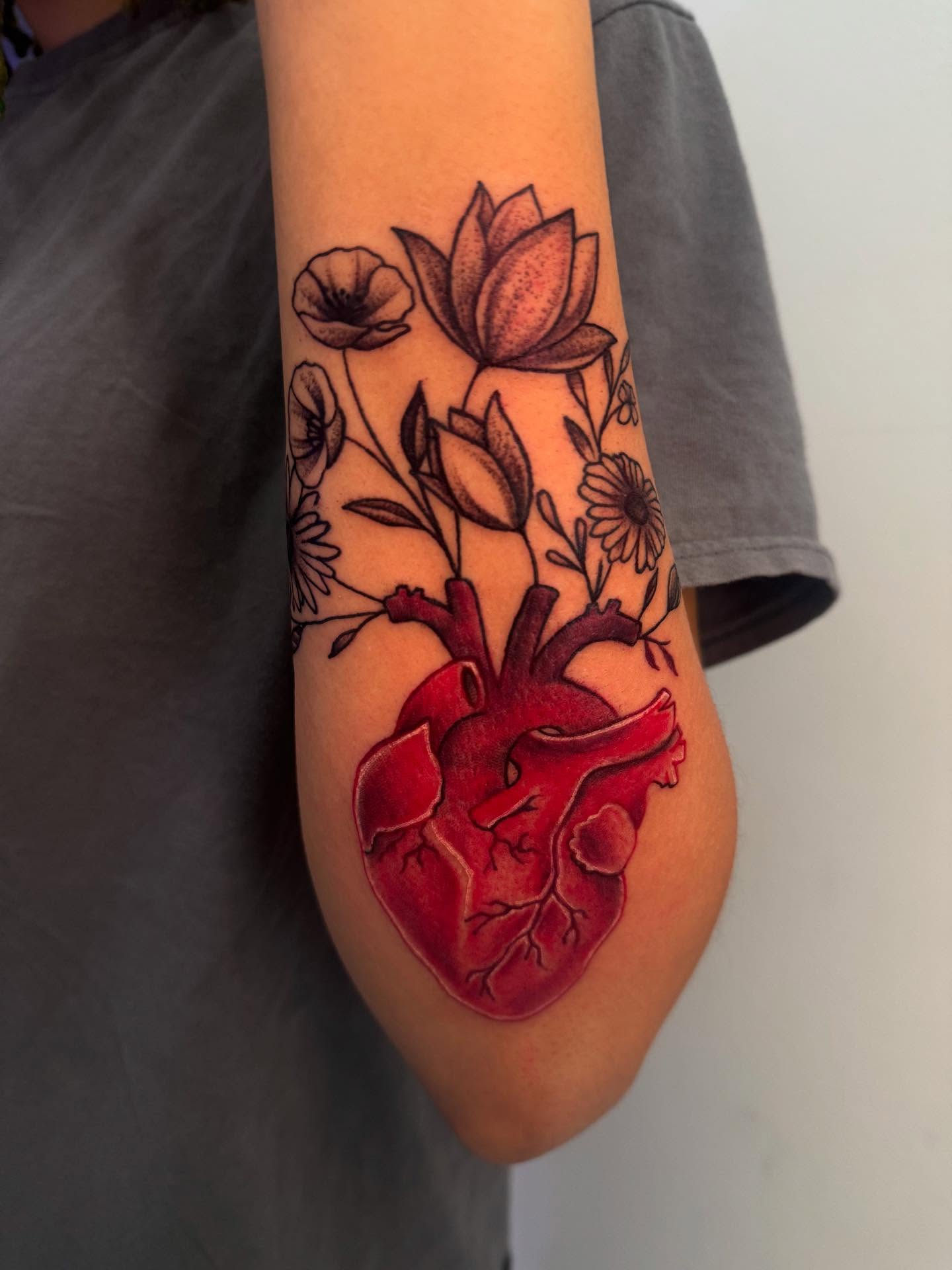 Heart with flowers realism tattoo on the forearm by The Ink Guru.
