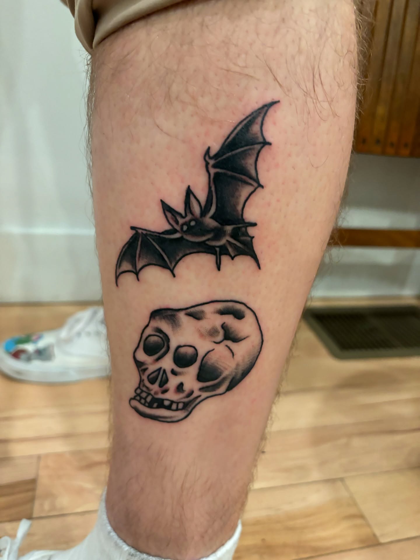Bat and skull black and grey tattoo on the thigh by Francis Cassidy