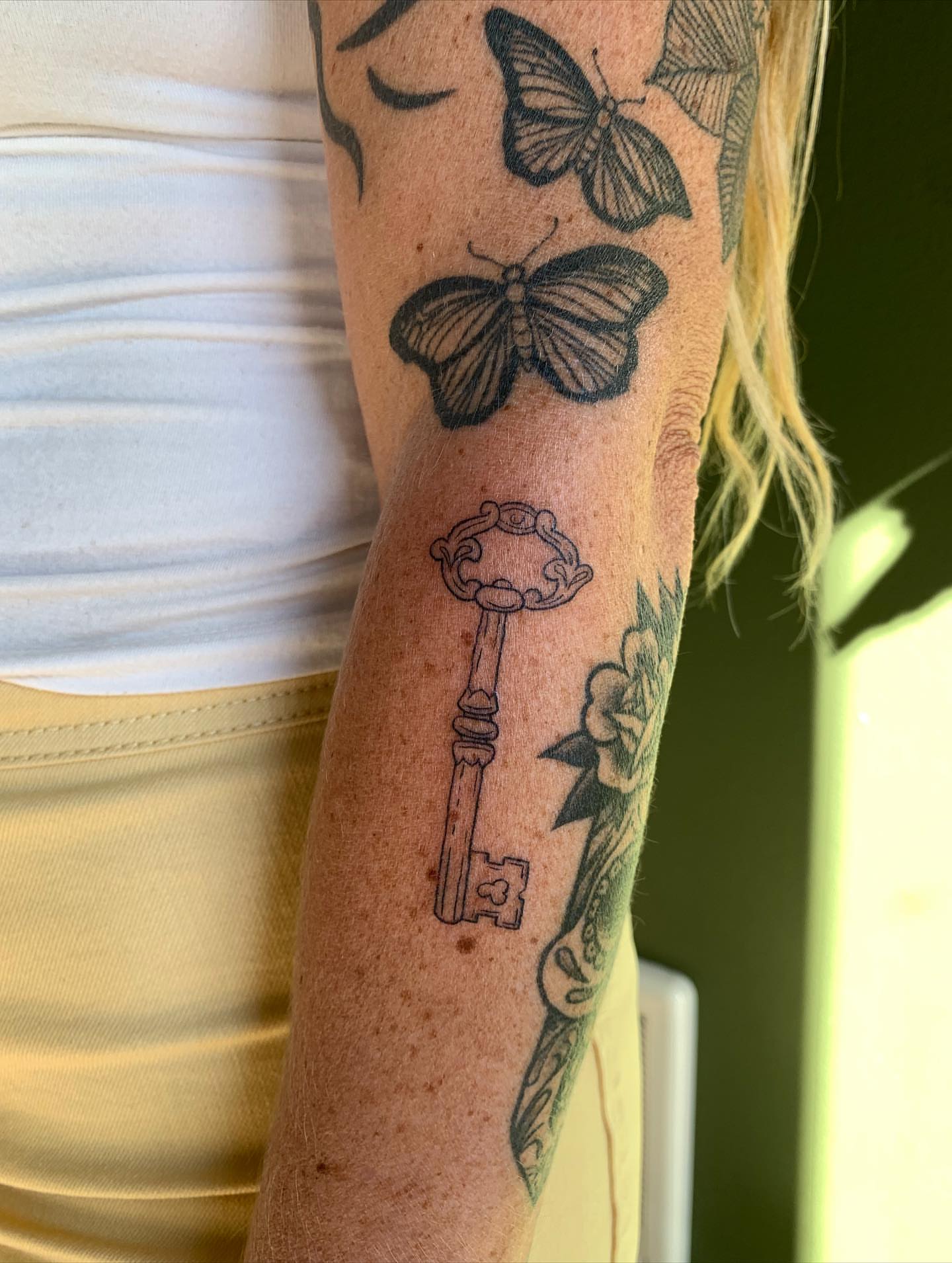 Key and butterfly black and grey tattoo on the forearm by ⊹ Avery Peterson ⊹