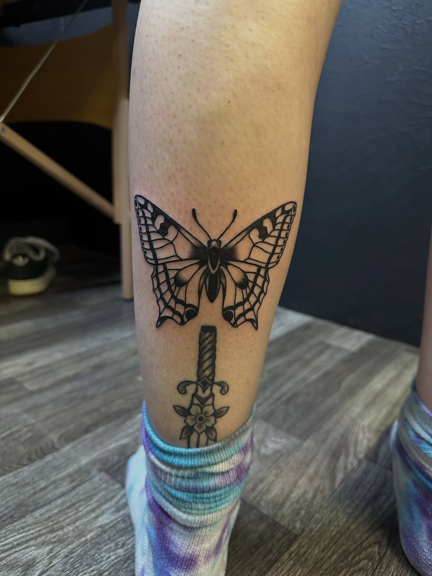 Butterfly and sword black and grey tattoo on the forearm by Ash Nicole Painterly, San Diego, California