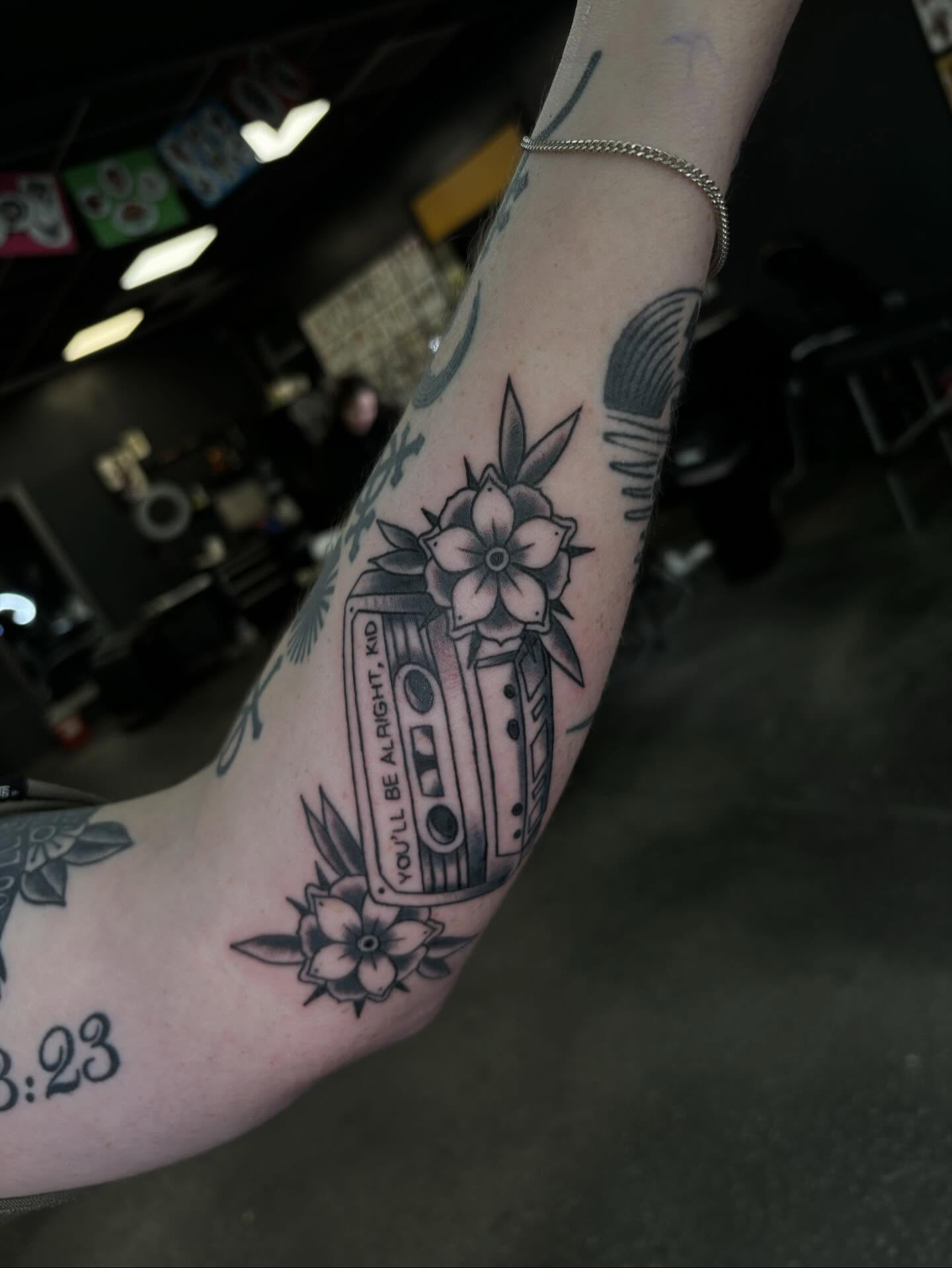 Cassette tape with flowers black and grey tattoo on the forearm by Brett Ferguson