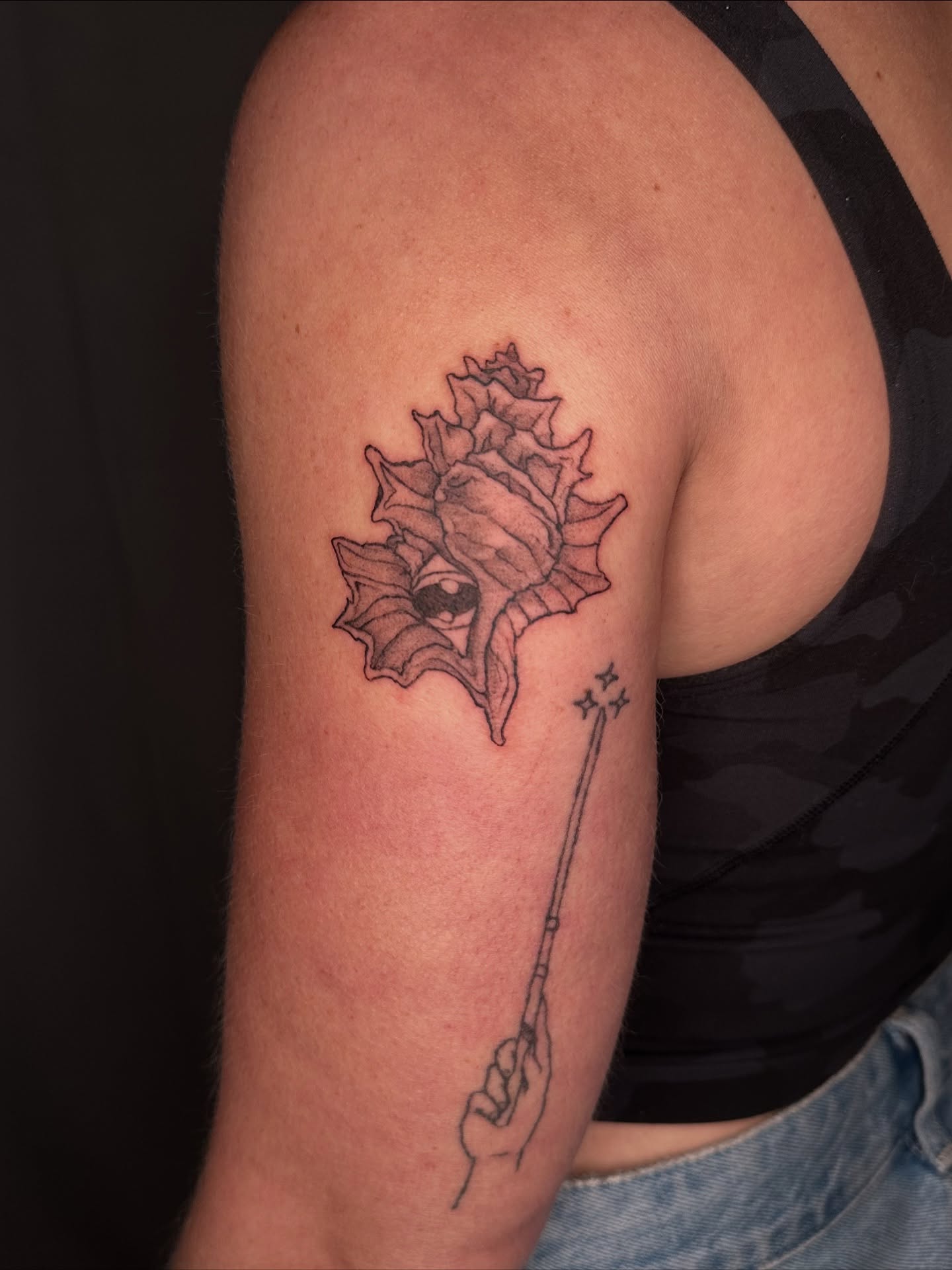 Shell and wand black and grey tattoo on the upper arm by Sadie Spades Philly Tattoos