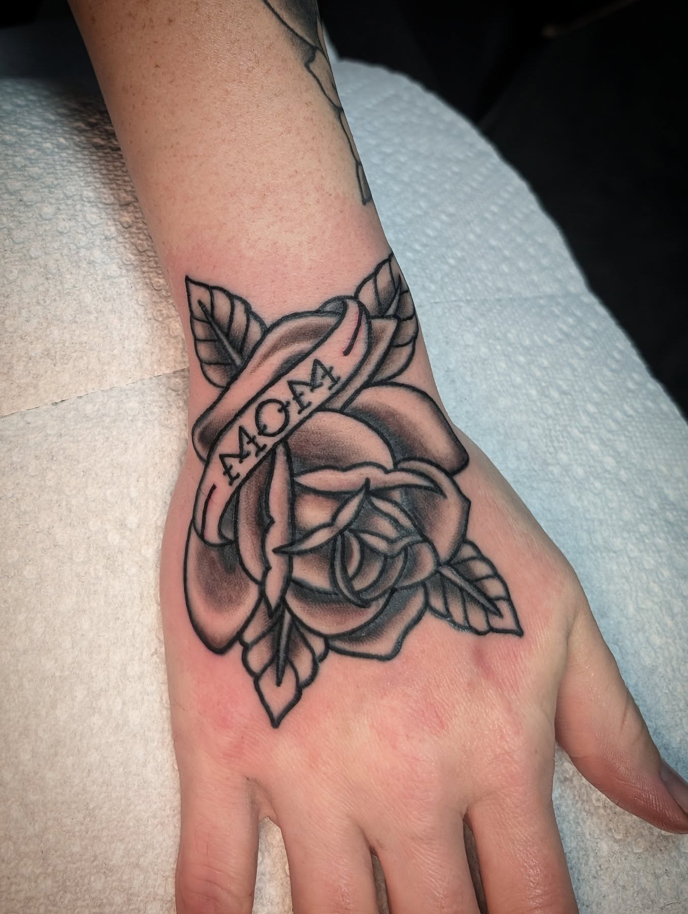 Rose and ribbon black and grey tattoo on the hand by Joe McElravy