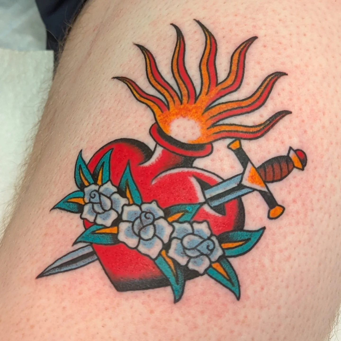 Heart with flames and swords American traditional tattoo on the forearm by Zack Mueller