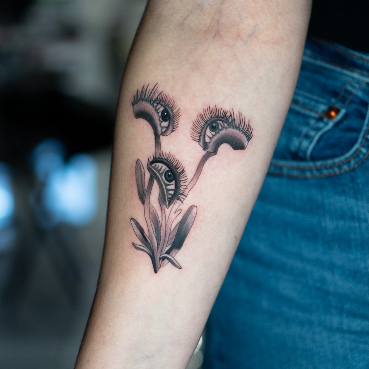 Eyelashes and flowers black and grey tattoo on the forearm by Jorden Ruppe