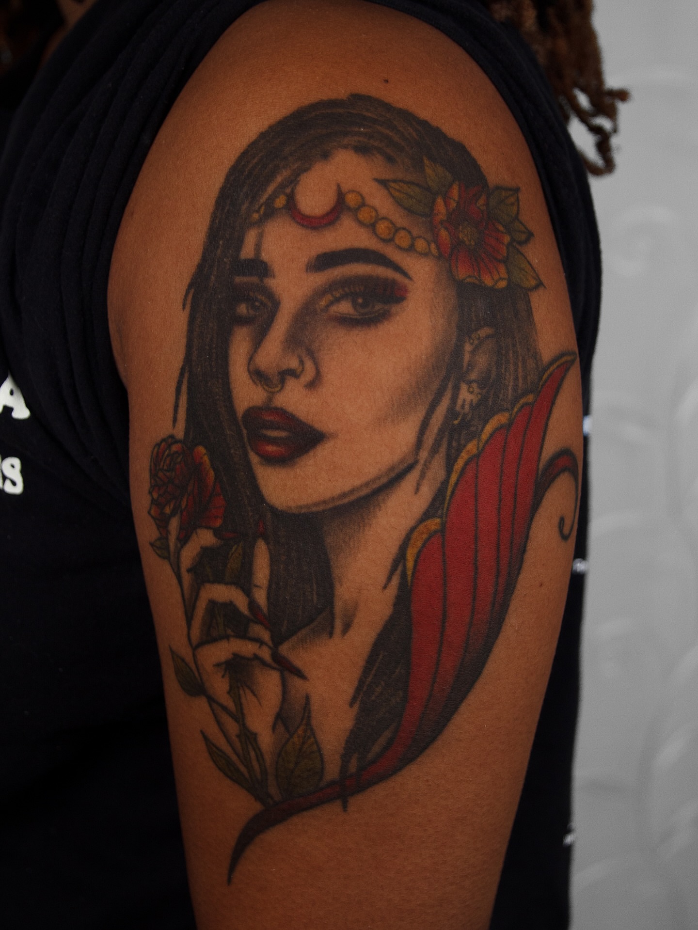 Woman with flowers realism tattoo on the shoulder by caliope yiannos