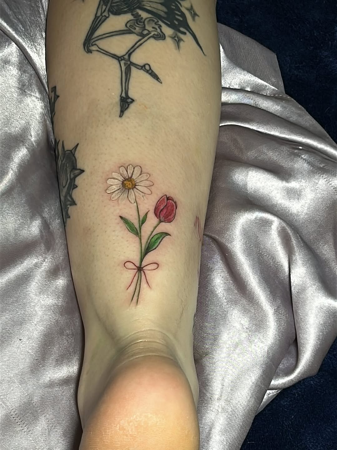 Daisy and tulip with bow tattoo on the forearm by JE
