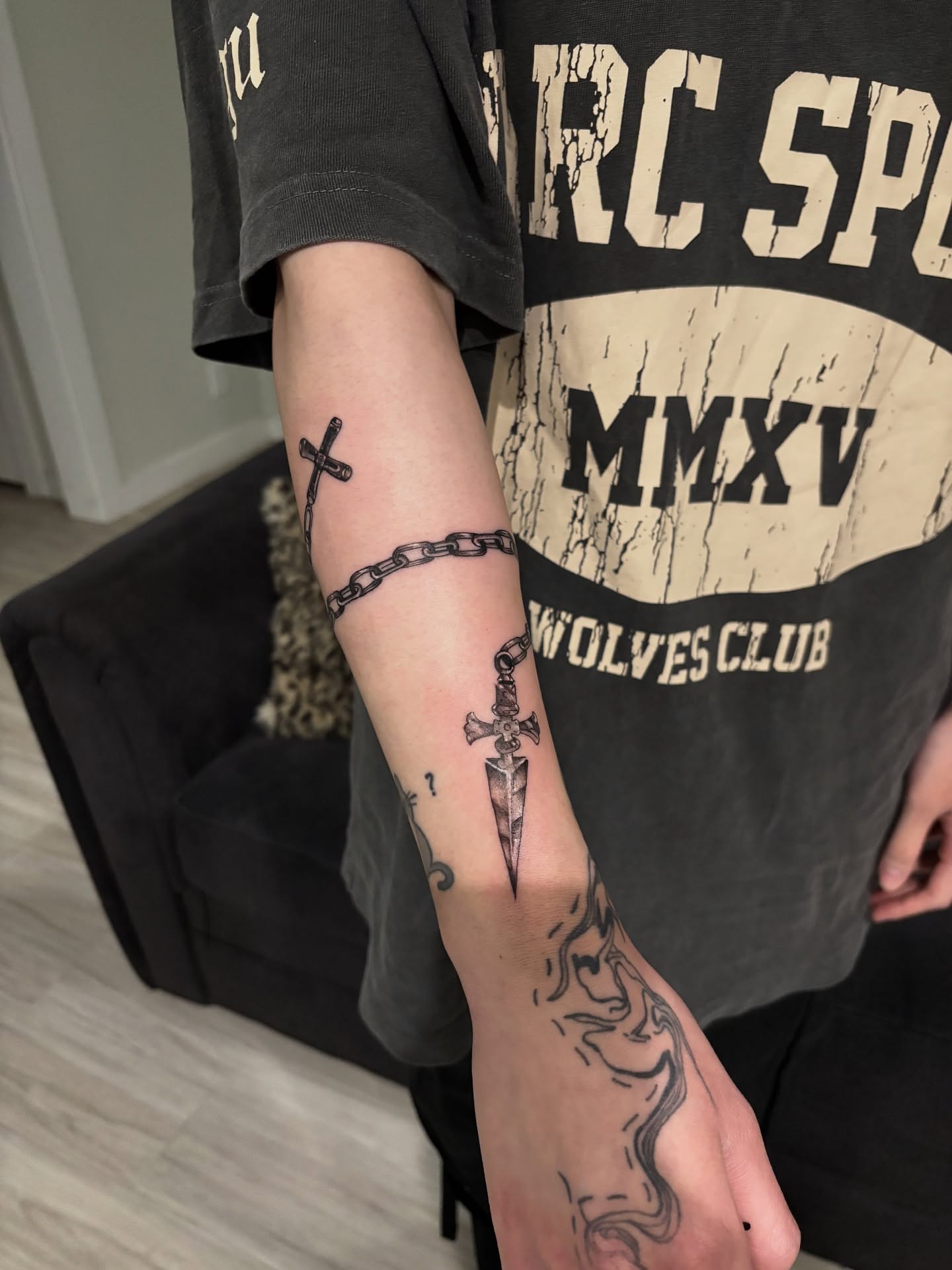 Cross, chain, dagger black and grey tattoo on the forearm by @miffythereaper