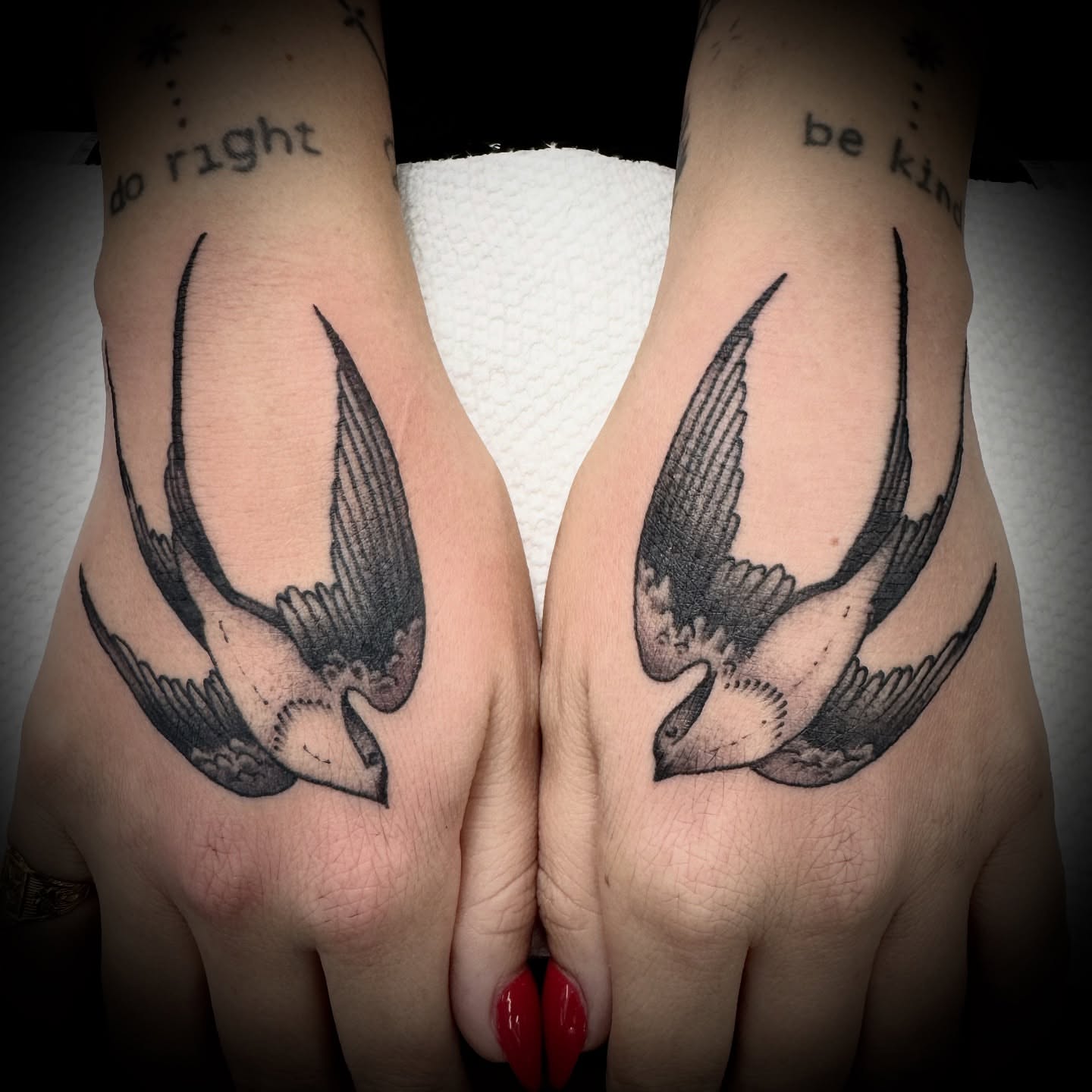 Swallows black and grey tattoo on the hand by Kristen