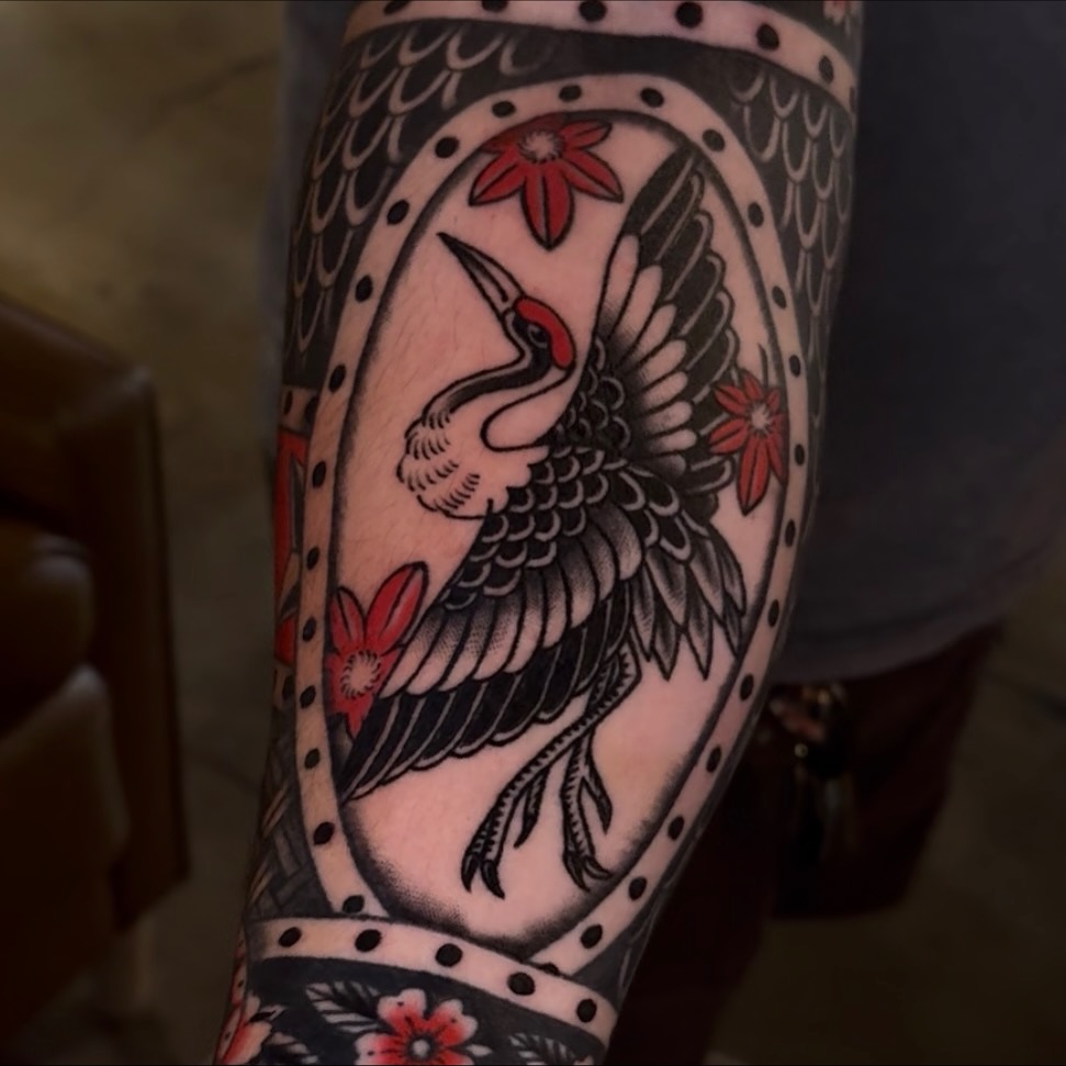 Crane and flowers American traditional tattoo on the forearm by Cory Allen