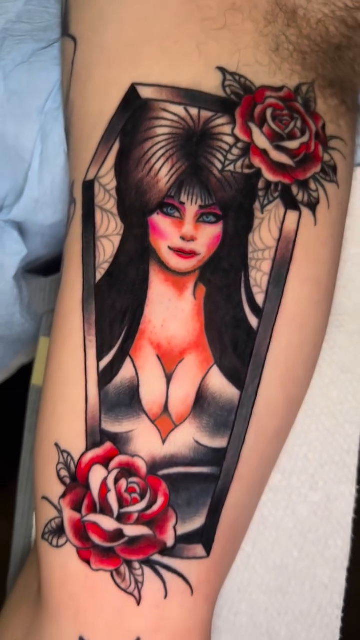Elvira in a coffin with roses neo-traditional tattoo on the forearm by Olivia Marie