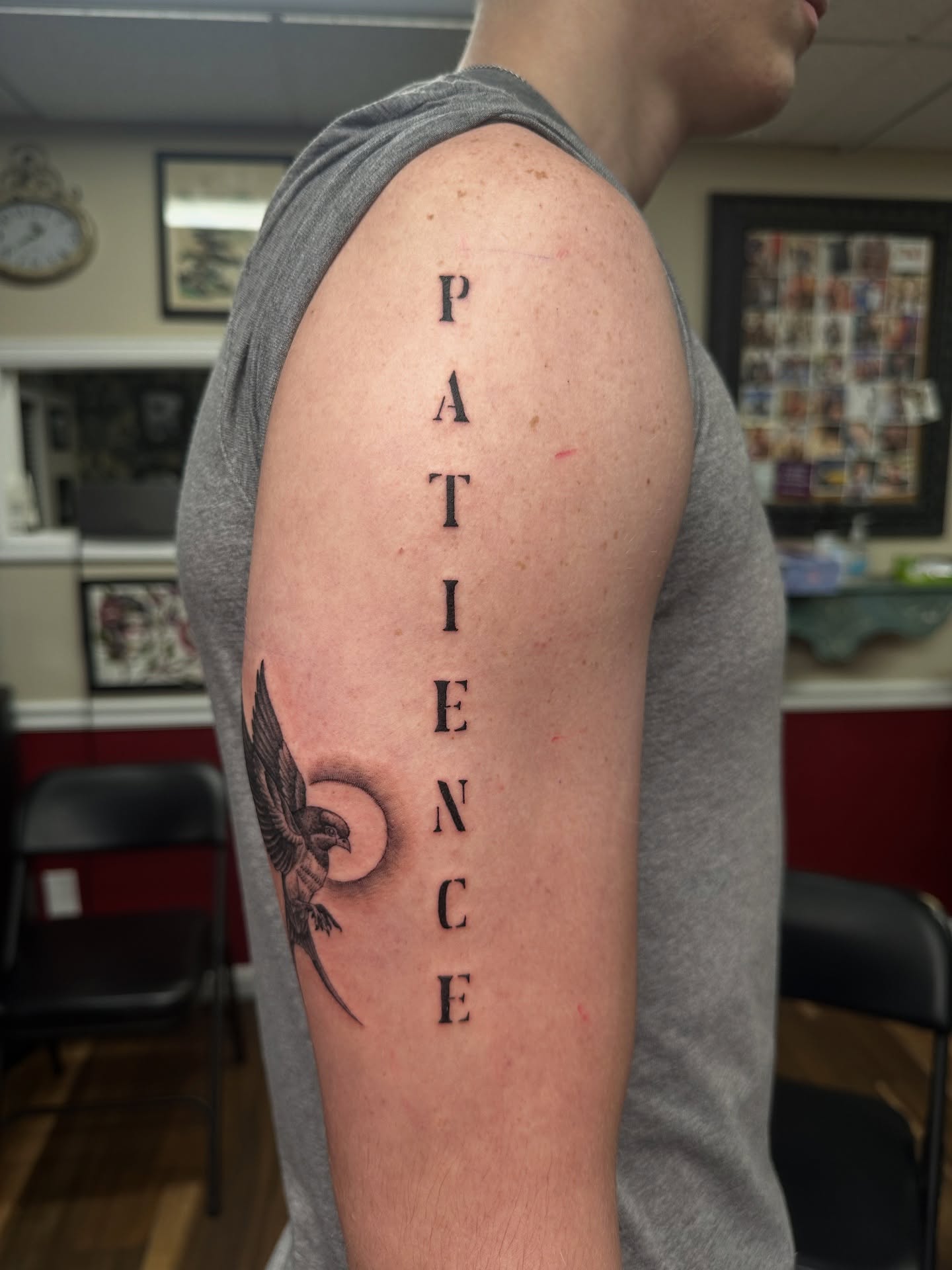 Patience black and grey tattoo on the upper arm by Bosco Layne