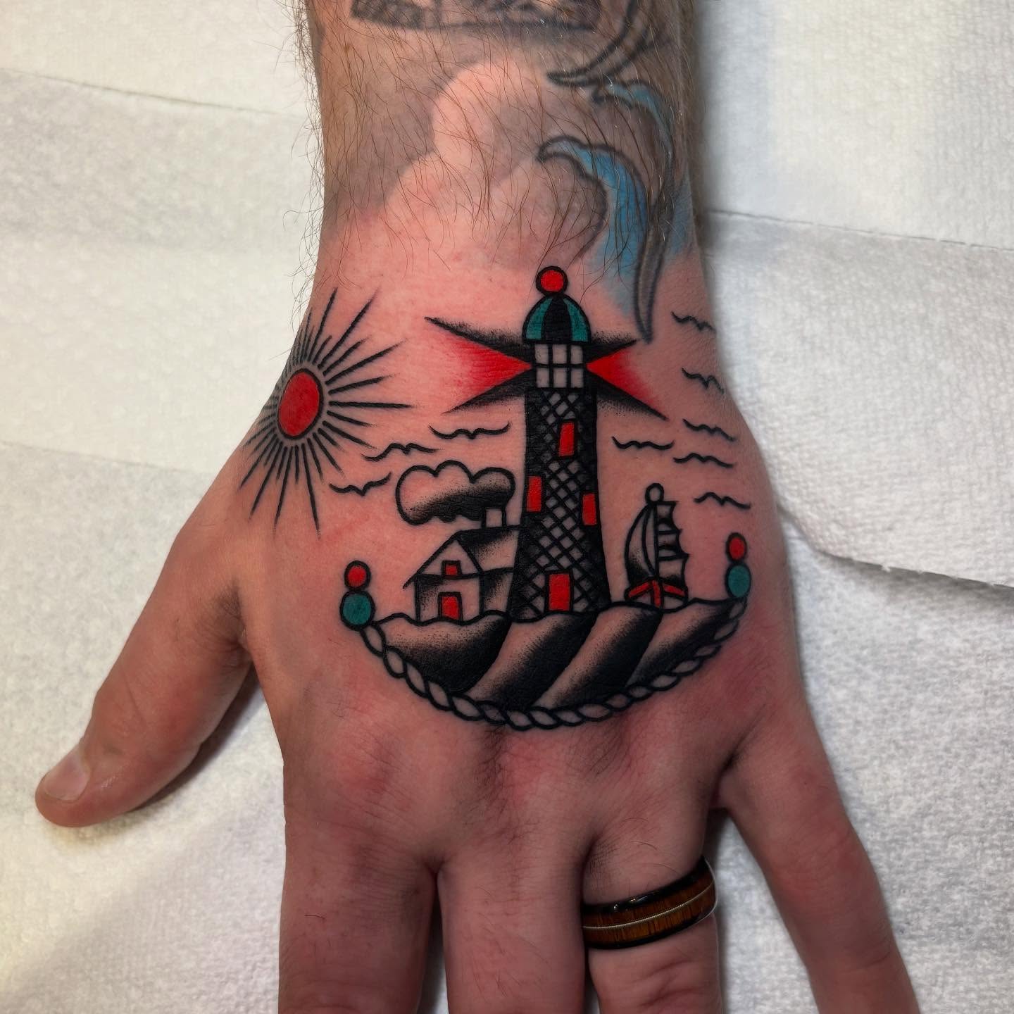 Lighthouse and ship American traditional tattoo on the hand by Texas Jonah