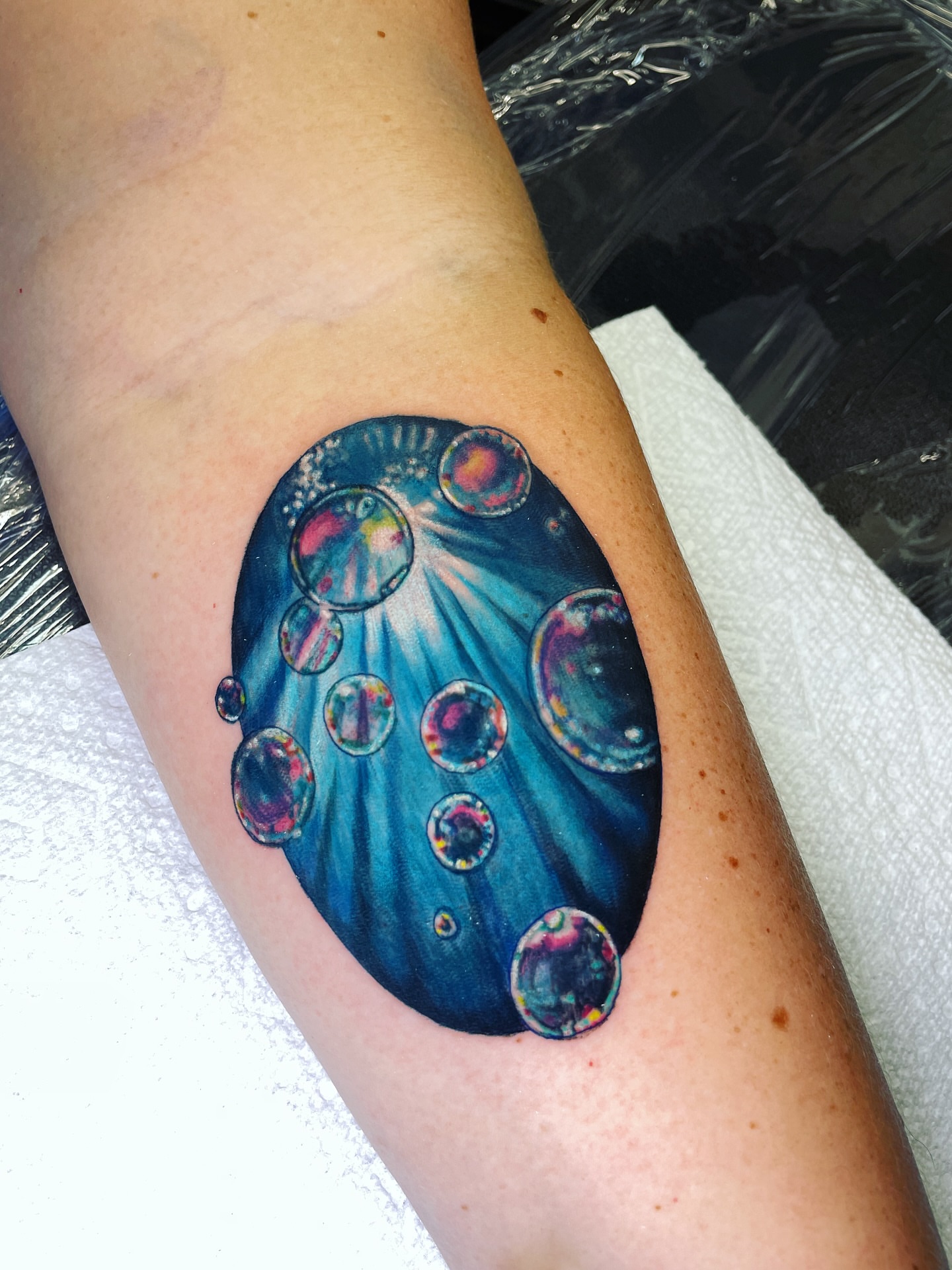 Soap bubbles watercolor tattoo on the forearm by Rick Elliott