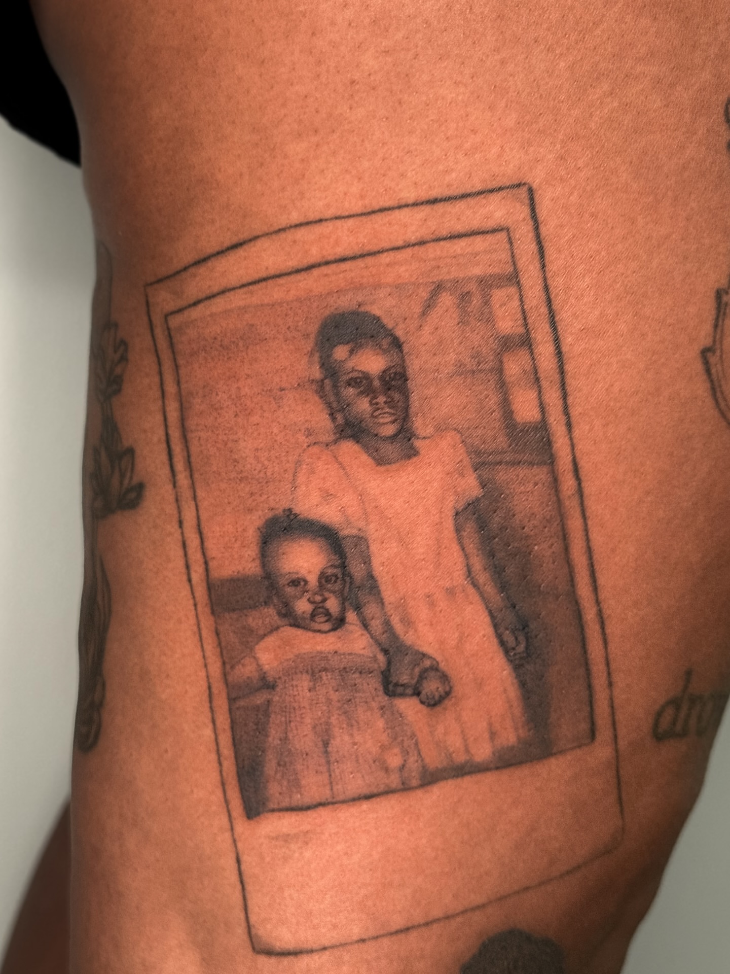 Polaroid photo black and grey tattoo on the thigh by Brows & Tattoos