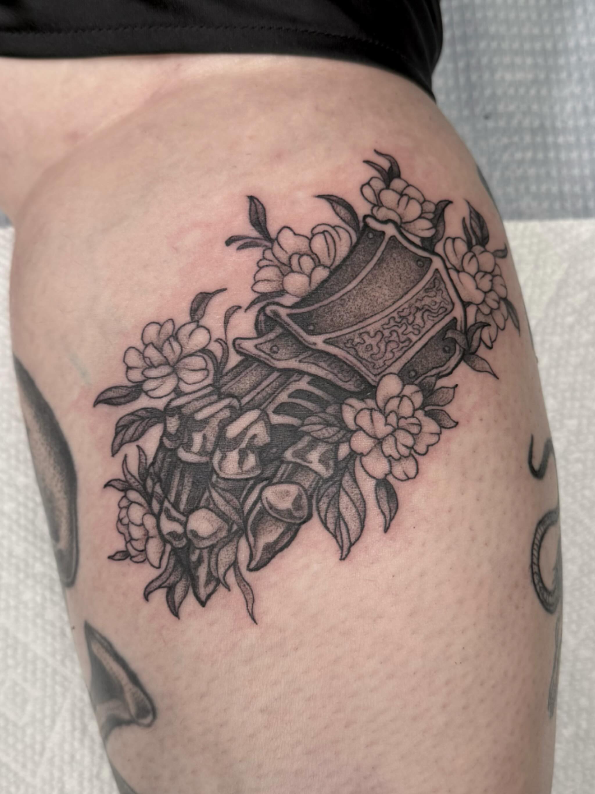 Floral arrangement with vase black and grey tattoo on the thigh by Hillary