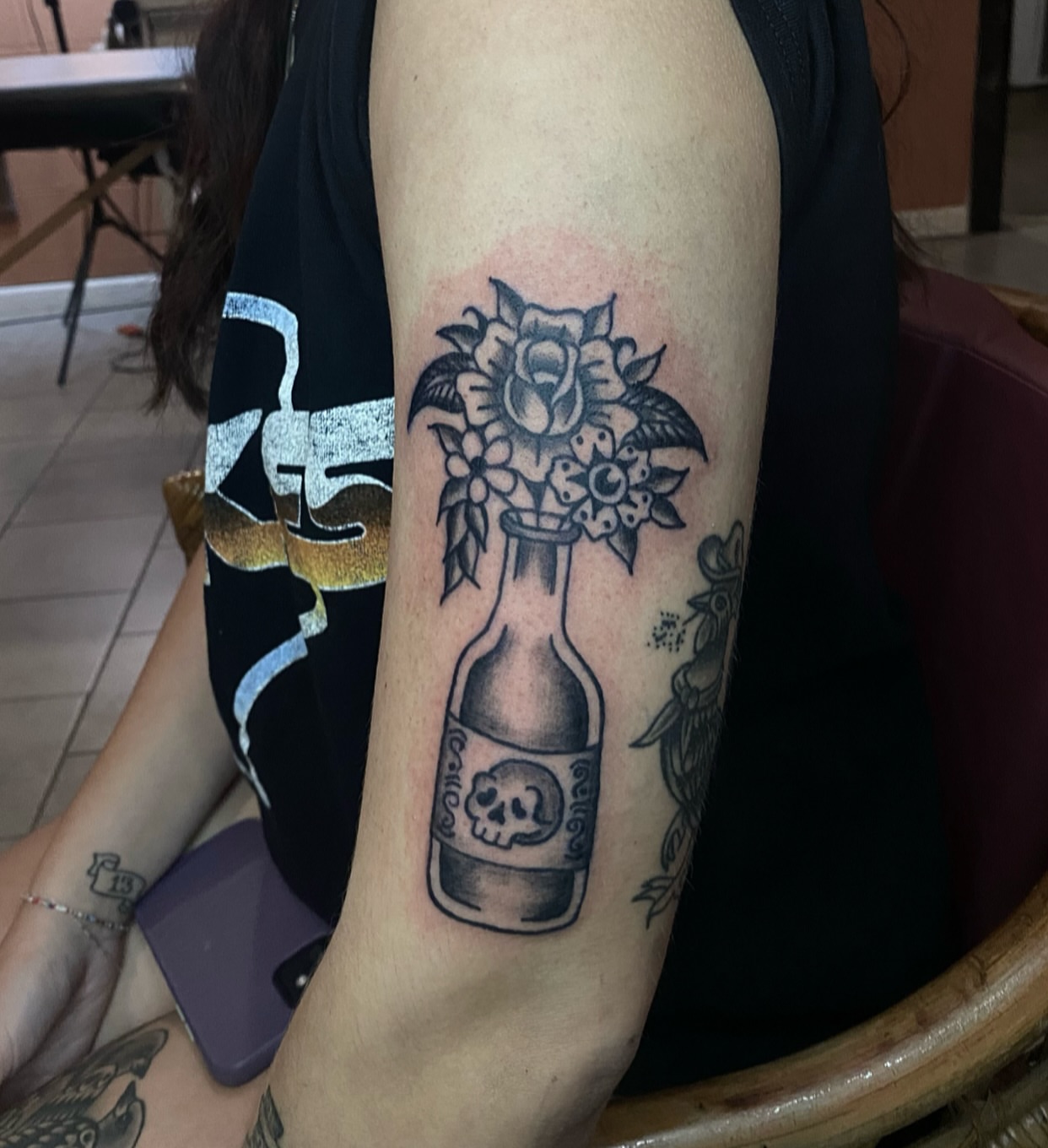 Beer bottle with flowers black and grey tattoo on the forearm by Myka King