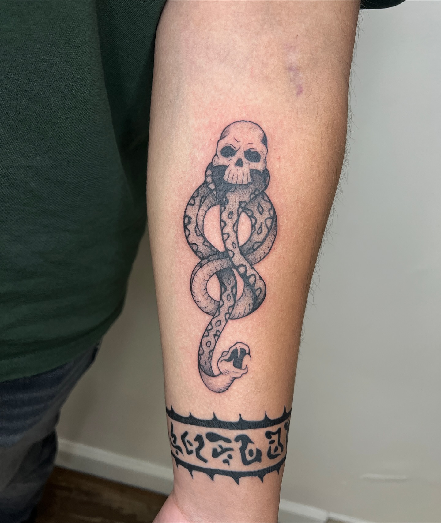 Snake and skull black and grey tattoo on the forearm by Diana García