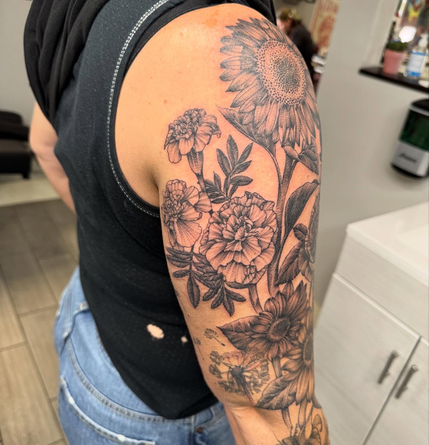 Sunflowers and marigolds realism tattoo on the upper arm by Joey Flaherty