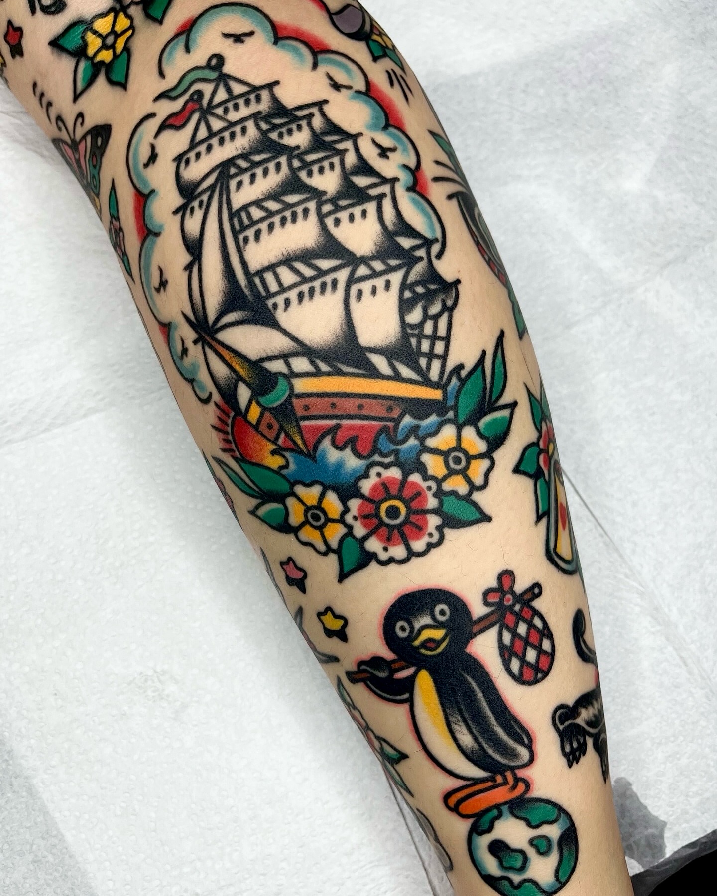 Ship and penguin American traditional tattoo on the forearm by 올드스쿨타투 레드립