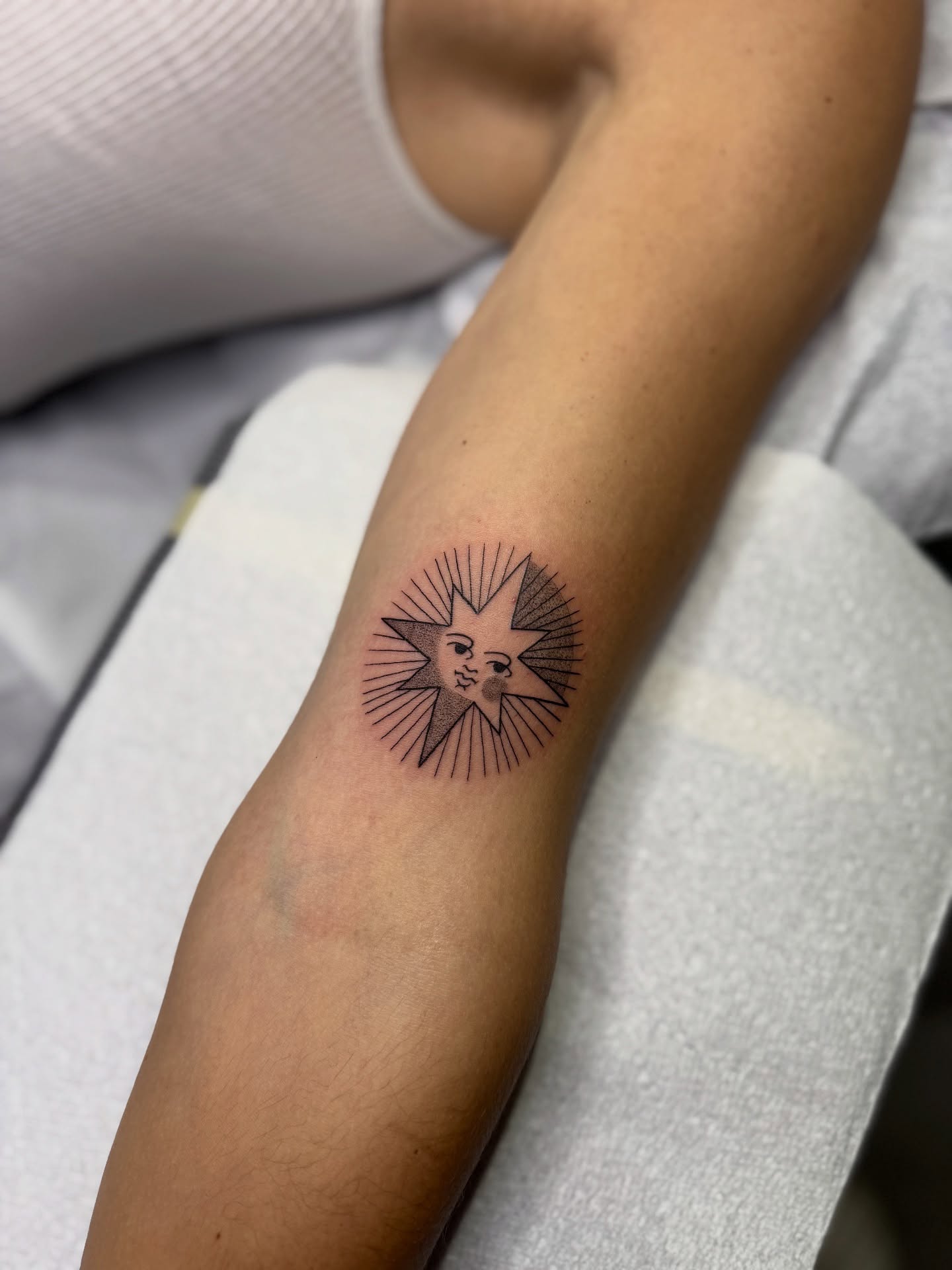 Sun with faces geometric tattoo on the forearm by Molly Jones