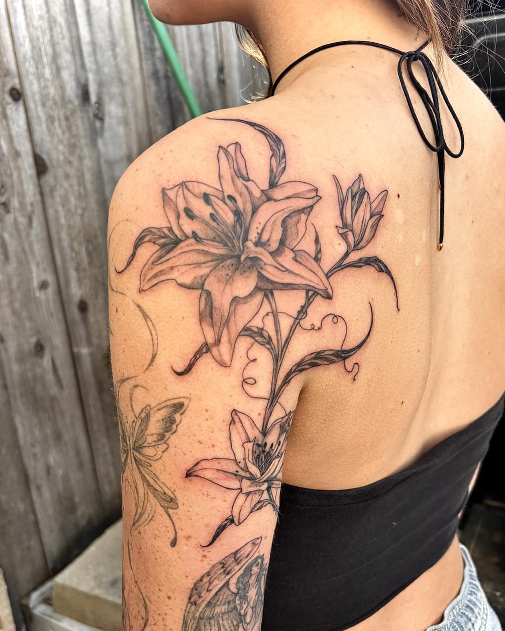 Lily black and grey tattoo on the shoulder by Quin Walker