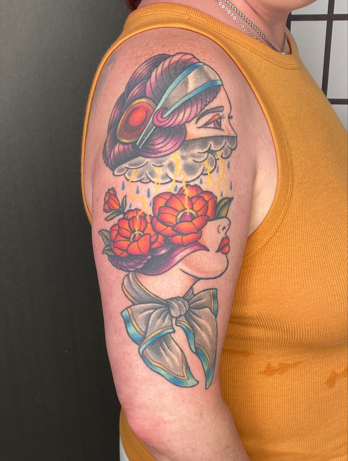 Woman with headphones and flowers American traditional tattoo on the upper arm by Leah Leinani