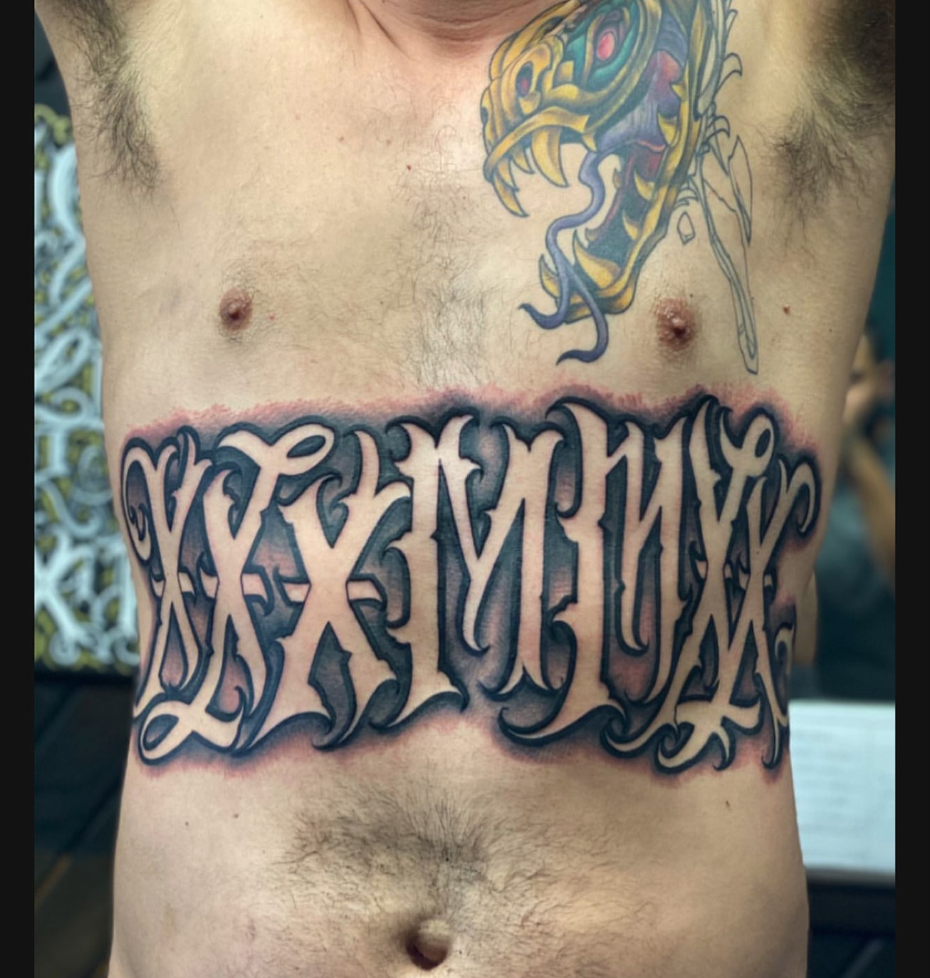 Gothic script tattoo on the chest by Lex Miranda
