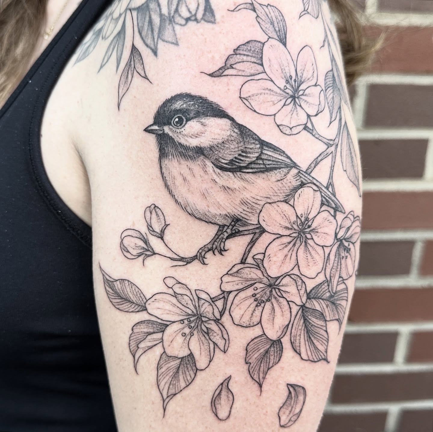 Bird and flowers black and grey tattoo on the upper arm by Robert McCollum