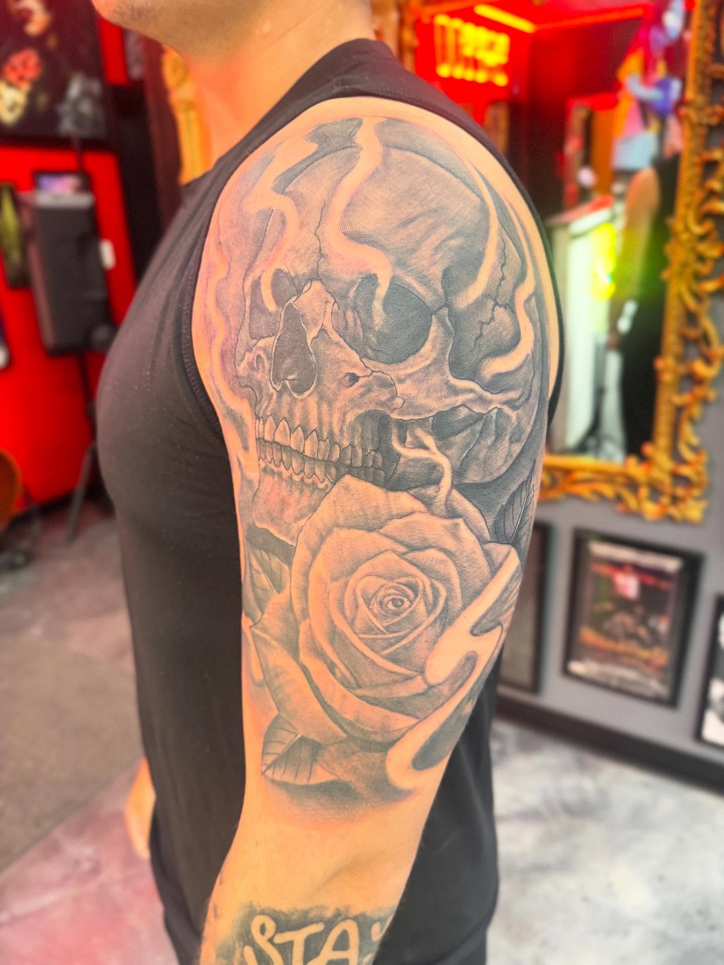Skull and rose realism tattoo on the upper arm by Alejandro Zaragoza
