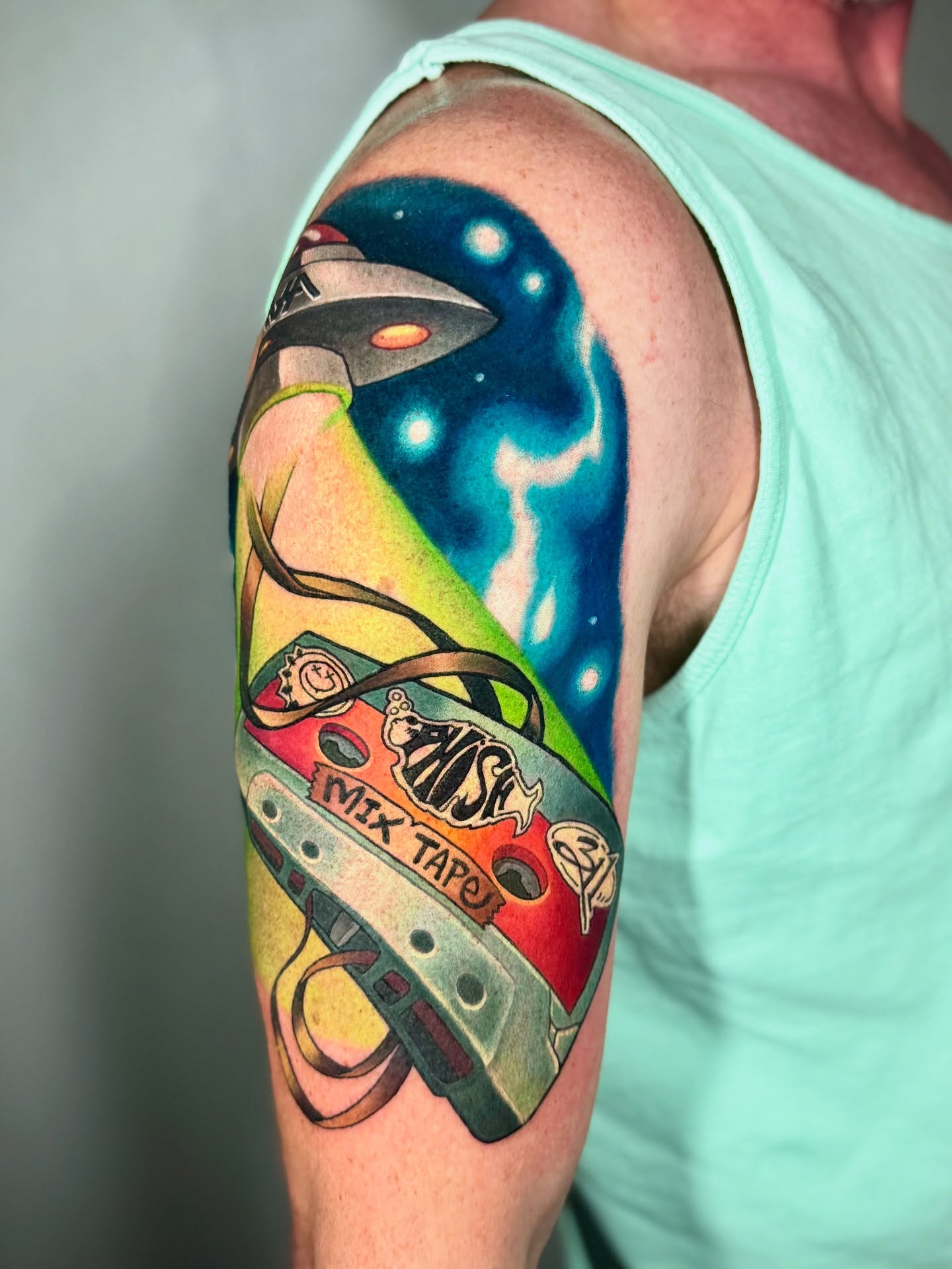 Space-themed mix tape new school tattoo on the upper arm by Kevin Boudreau Newschool Tattoos